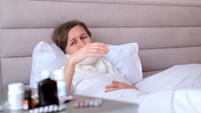 A young woman has a cough and feels unwell in a cold apartment without heating. The woman caught a cold.