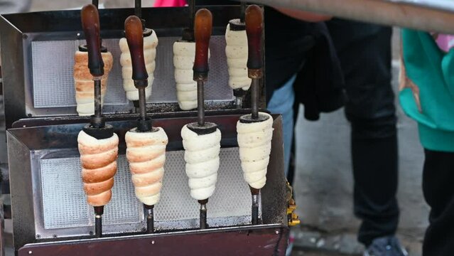 At a street food stall in Prague preparation and sale of cimney cacke, in the local language Trldo. The dough cooks while rotating on the wooden support.