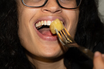 Bouche d'une jeune femme en train de manger avec une fourchette - obrazy, fototapety, plakaty
