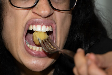 Bouche d'une jeune femme lors d'un repas avec une fourchette et un morceau de pomme de terre - obrazy, fototapety, plakaty