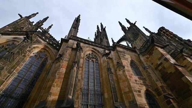 Prague, Czech Republic, August 4,2023. Footage with iconic image of the cathedral of San Vitus shot from below with a wide-angle lens: the pan movement scrolls the amazing Gothic spiers.
