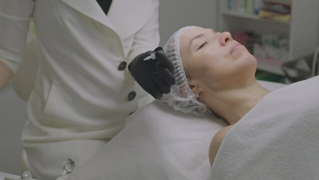 Close-up of a woman face. Needle mesotherapy procedure into the skin of the face