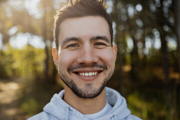 Portrait of young attractive man smiling into the camera in forest 
