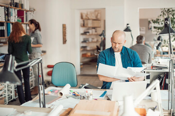 Fototapeta premium Middle aged Caucasian architect working on building plans in a modern company office