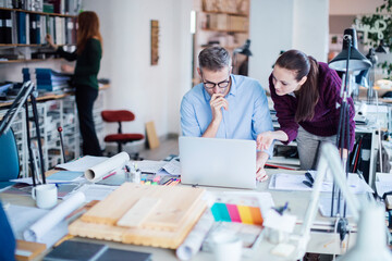 Obraz premium Young man and woman using the laptop while working together on a project in a startup company office