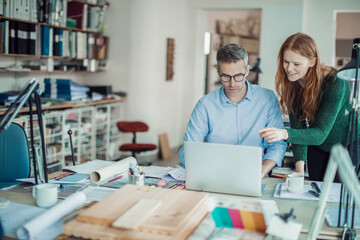 Obraz premium Young man and woman using the laptop while working together on a project in a startup company office