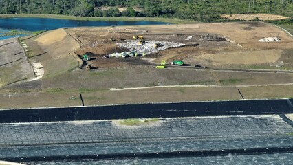 Waste management concept. Large landfill site with bulldozers burying trash under ground. Harmful impact of modern consumerism on environment - Powered by Adobe