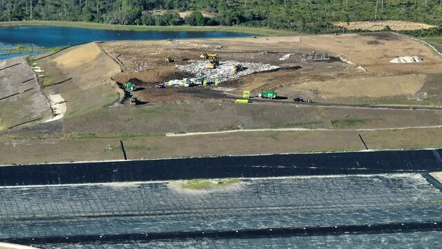 Waste management concept. Large landfill site with bulldozers burying trash under ground. Harmful impact of modern consumerism on environment