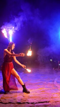 young woman fire dancer performing outdoors at night