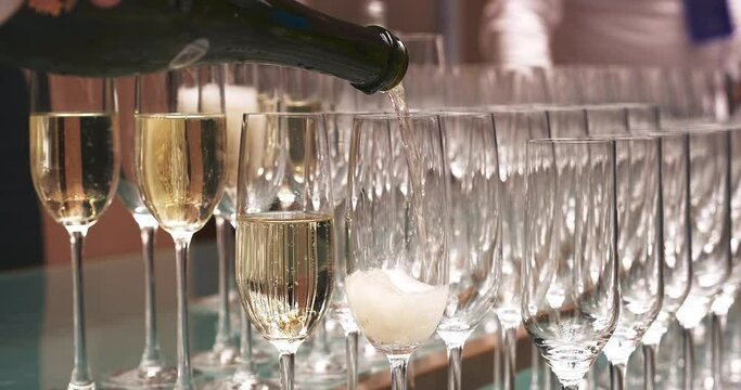 Waiter is pouring champagne. Pour the champagne into a glass. Champagne pouring in glass. Gala evening, meeting, conference, reception and party concept. Close-up, slow motion