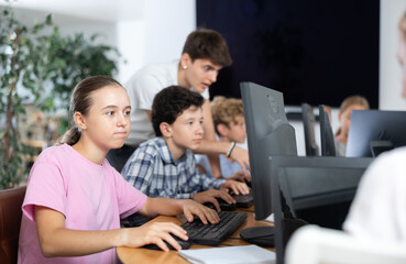 Girl student learns to work with computer in group at lesson