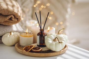 Autumn cozy mood composition on the windowsill. Aroma diffuser, pumpkins, dry citrus, candles on...