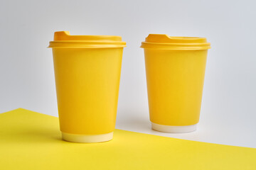 Disposable yellow paper cup on a light background. Mock up 
