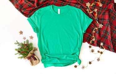 Flat lay mock up of heather green tshirt with Christmas accessories. X mas 3001 t shirt top view and white background