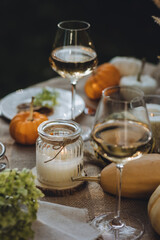 Fall still-life. Orange pumpkins, dry flowers and candles on linen tablecloth. Dinner table outdoors in the garden. Cozy autumn concept., simple handmade decoration, countryside style