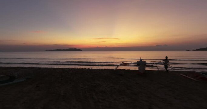 Sunset drone view of people next to a traditional boat in El Nido, Philippines