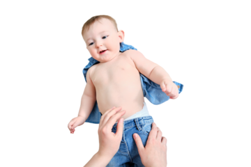 A mother woman puts on jeans pants for a baby boy, isolated on a white background. Mom dresses a happy child in clothes. Kid nine months old