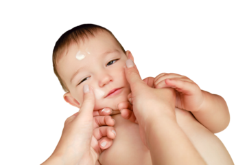 Mother smears cream on the face of a happy toddler baby boy, isolated on a white background. Mom smears ointment on the skin of a smiling child. Kid age one year
