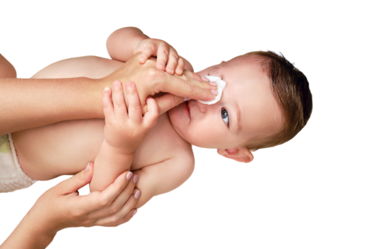 A mother washes eyes of a happy toddler baby boy with a cotton pad, isolated on a white background. Mom cleanses the skin on the face of a smiling child. Kid age one year