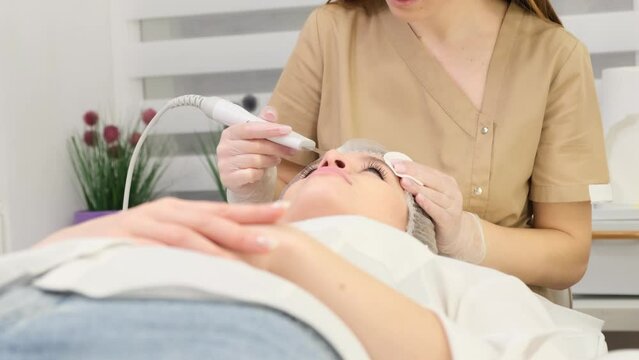 The patient lies in the office of a beautician on the procedure of hardware facial cleansing. 