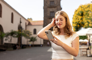 Fototapeta premium happy woman walking and using a smart phone on a city street