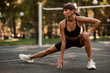 A young, athletic woman is exercising on the sports field. The concept of weight loss. Beautiful figure. Fintes exercise