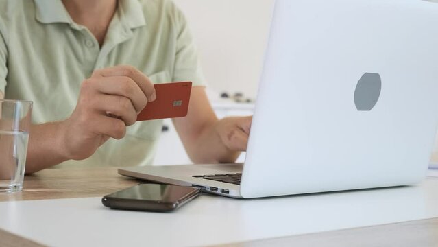 Man holding credit card and typing on laptop for online shopping and payment, makes a purchase in internet. Male at home shopping online. E commerce 