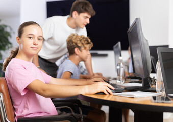 Minor female student posing while sitting at computer table in training room
