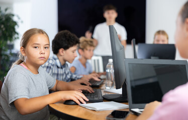 Concerned preteen girl working with computer programs with interest in training room