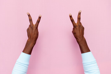 african american male hands show peace sign and number four on pink isolated background