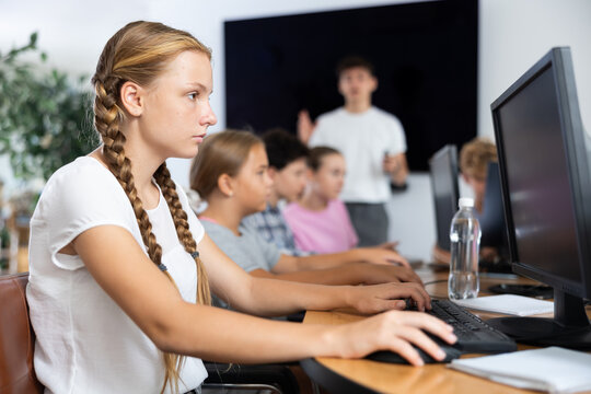 Girl student learning to use computer in group in classroom