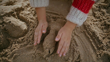 Kid hands building sand castle on seashore weekend. Creative boy enjoying game