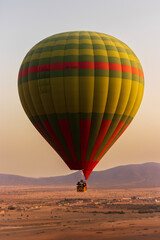 Fototapeta premium Hot balloon flying at sunset over the Atlas Mountains in the desert of Morocco 