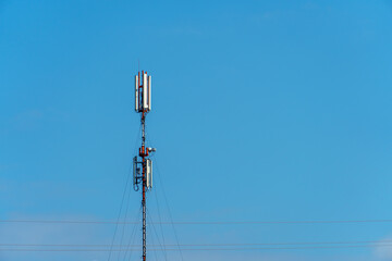 New GSM antennas on a high tower against a blue sky for transmitting a 5g signal are dangerous to health. Radiation pollution of the environment through cell towers. The threat of extinction