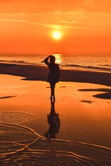 Woman on the seashore in a beautiful evening scenery. Girl walking on the beach with the setting sun in the background. Photo taken at the Baltic Sea in Leba, Poland. - 659687290