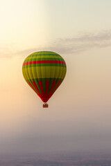 Hot balloon flying at sunset over the Atlas Mountains in the desert of Morocco 