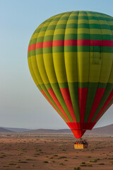 Hot balloon flying at sunset over the Atlas Mountains in the desert of Morocco 