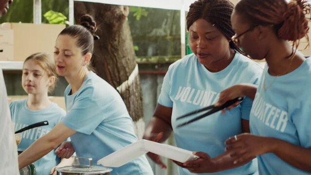 Homeless and refugee shelter receives donations and distributes to needy with help from humanitarian aid organization. At non-profit food bank, female volunteers share free meals to less privileged.