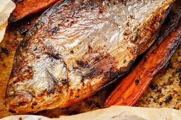 Close-up of baked dorado fish wrapped in parchment paper with carrots. Mediterranean food concept