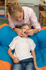 Speech therapist using logopedic probe on session with little boy. Speech therapy tongue massage to a child with a staging probe. Female physiotherapist working on speech defects with preschool boy.