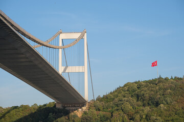 Bosphorus bridge photography from below angle with blue sky, forest and Turkish flag in İstanbul. 