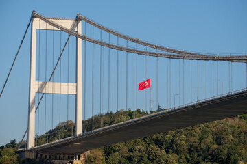Bosphorus bridge photography from below angle with blue sky, forest and Turkish flag in İstanbul. 