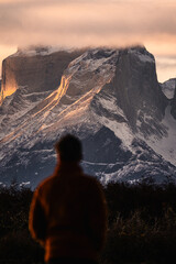 unrecognizable out-of-focus person contemplating the mountains in focus at sunset, Torres del Paine national park, Chile