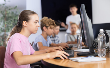 Girl student learns to work with computer in group at lesson