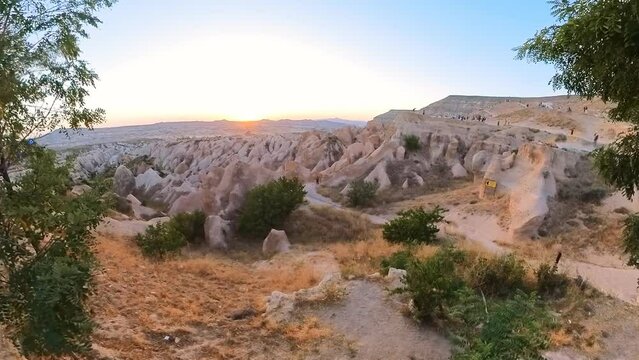 woman gazing at sunset over picturesque Red Valley Park in heart of Cappadocia in Turkey. Sun's warm glow bathes the surreal landscape in a romantic and golden light, creating an enchanting scene