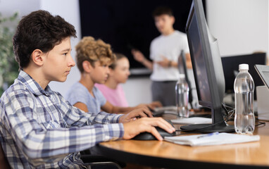 Curious underage boy engaged in IT training during computer courses for children