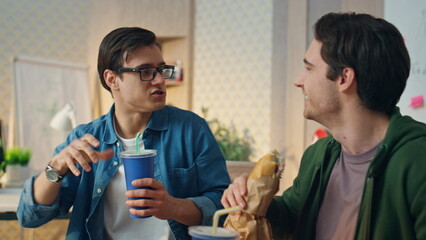Happy colleagues eating lunch looking monitor close up. Freelancers discussing