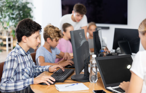 Concerned preteen boy working with computer programs with interest in training room