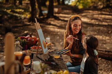 Mother and daughter painting fruits during forest picnic