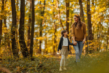 Fototapeta premium Mother and daughter exploring the forest during autumn